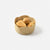 A round basket, crocheted with natural raffia, with small bread rolls inside, on a light grey background.
